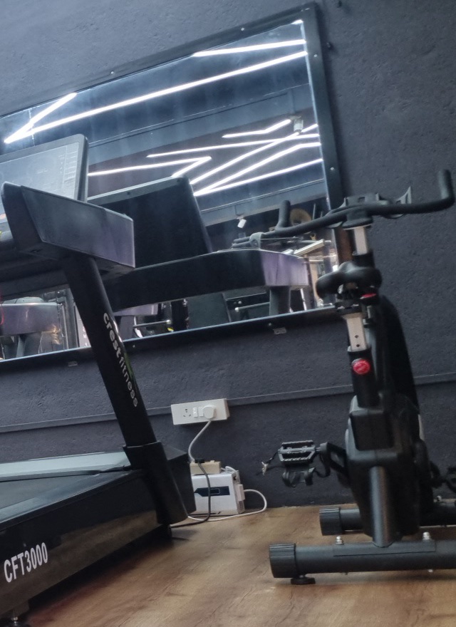 Exercise bike beside the wall mirror, with the ceiling lights reflected in it